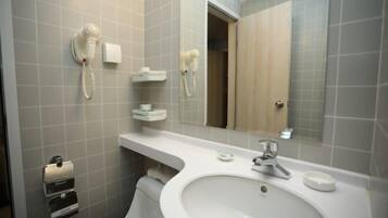 Un baño con lavamanos, espejo, toallero y secador de pelo en la pared.