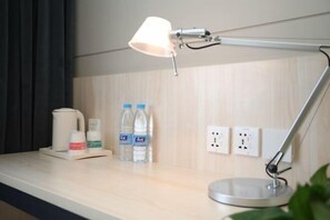 A hotel room with a desk, a lamp, a kettle, and two bottles of water. - Jin Xing Holiday Hotel (Pingliang Kongtong District Green Square Branch) (Pingliang)