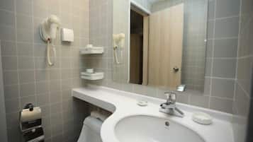 Un bagno con un lavandino bianco, uno specchio, un portasciugamani e un asciugacapelli a parete.