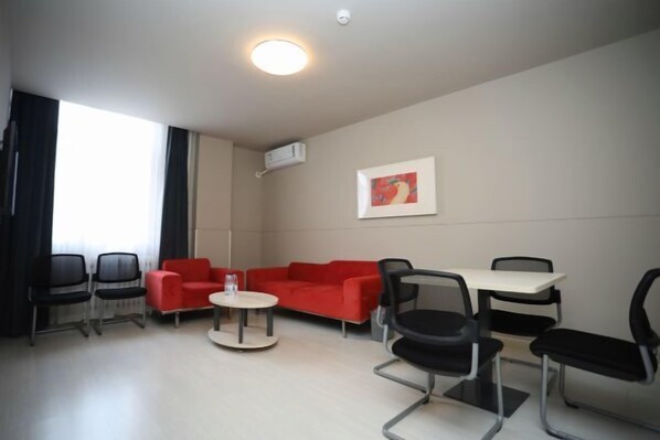 A modern room with a red sofa, black chairs, a round table, and a white ceiling light. - Jin Xing Holiday Hotel (Pingliang Kongtong District Green Square Branch) (Pingliang)
