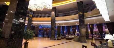 A spacious lobby with marble columns, a reception desk, and a seating area.