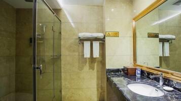 A hotel bathroom with a glass-enclosed shower, a marble sink, and a large mirror.