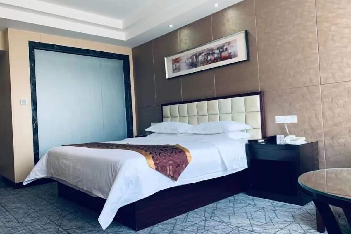 Habitación de hotel con cama, mesita de noche, mesa y un cuadro en la pared.