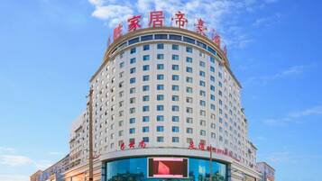 A multi-story hotel with a prominent sign at the top, a large glass facade on the lower level, and a clear blue sky in the background.