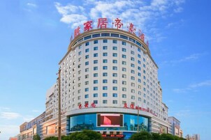 A multi-story hotel with a prominent sign at the top, a large glass facade on the lower level, and a clear blue sky in the background.