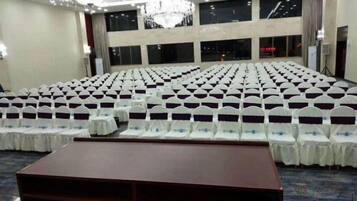 Un amplio salón de conferencias con filas de sillas, un atril y suelo alfombrado.