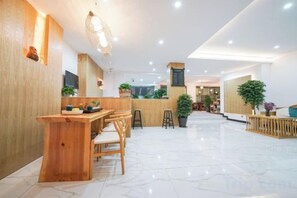 A spacious lobby with a reception desk, seating area, and potted plants. - GW. Flower Time (Ninglang)