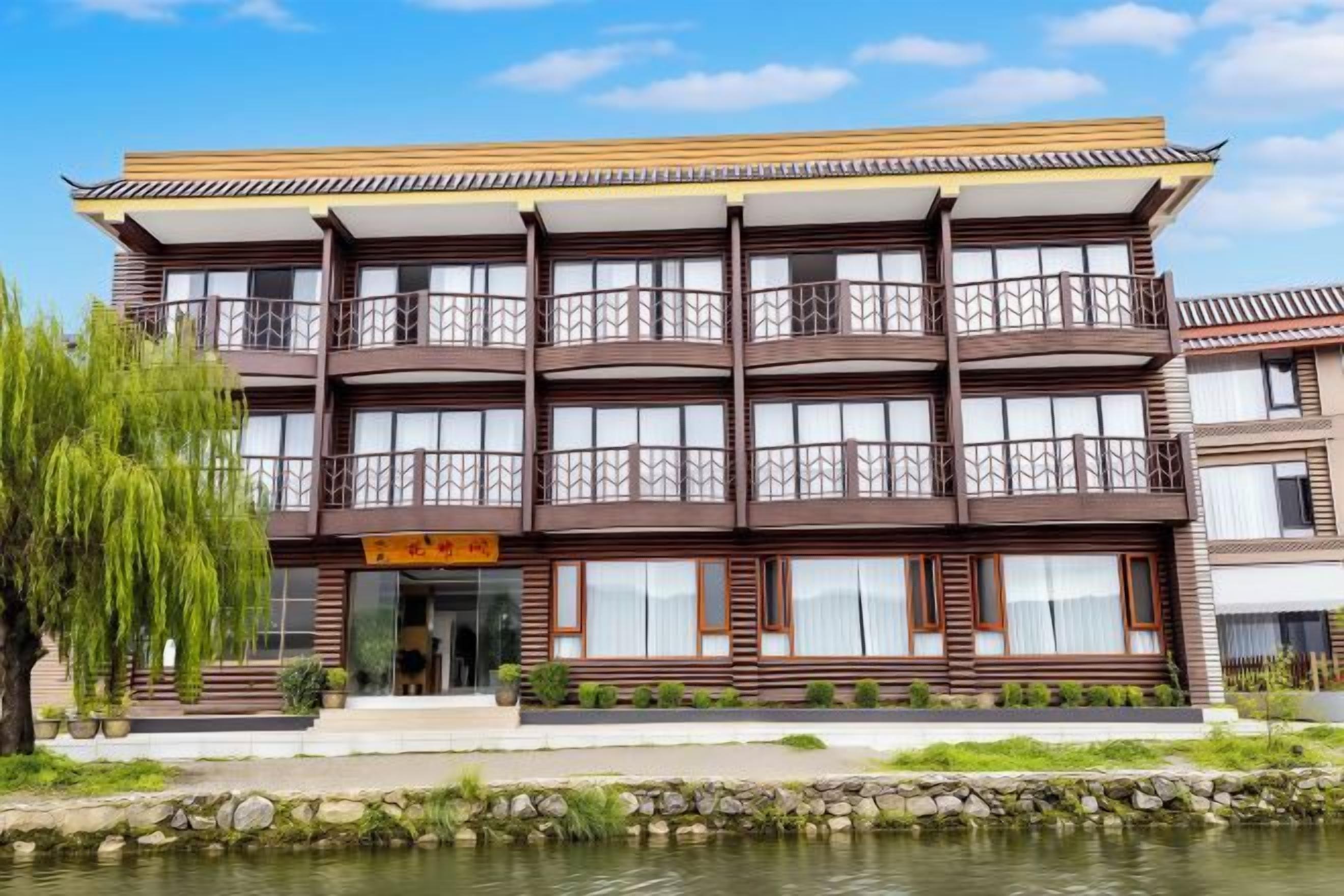 Un edificio de varios pisos con balcones, un estanque en primer plano y un cielo despejado.