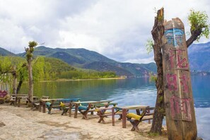 Zona de picnic junto al lago, con bancos de madera y un poste de indicaciones.