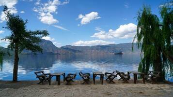 A lakeside seating area with stone flooring and wooden furniture.