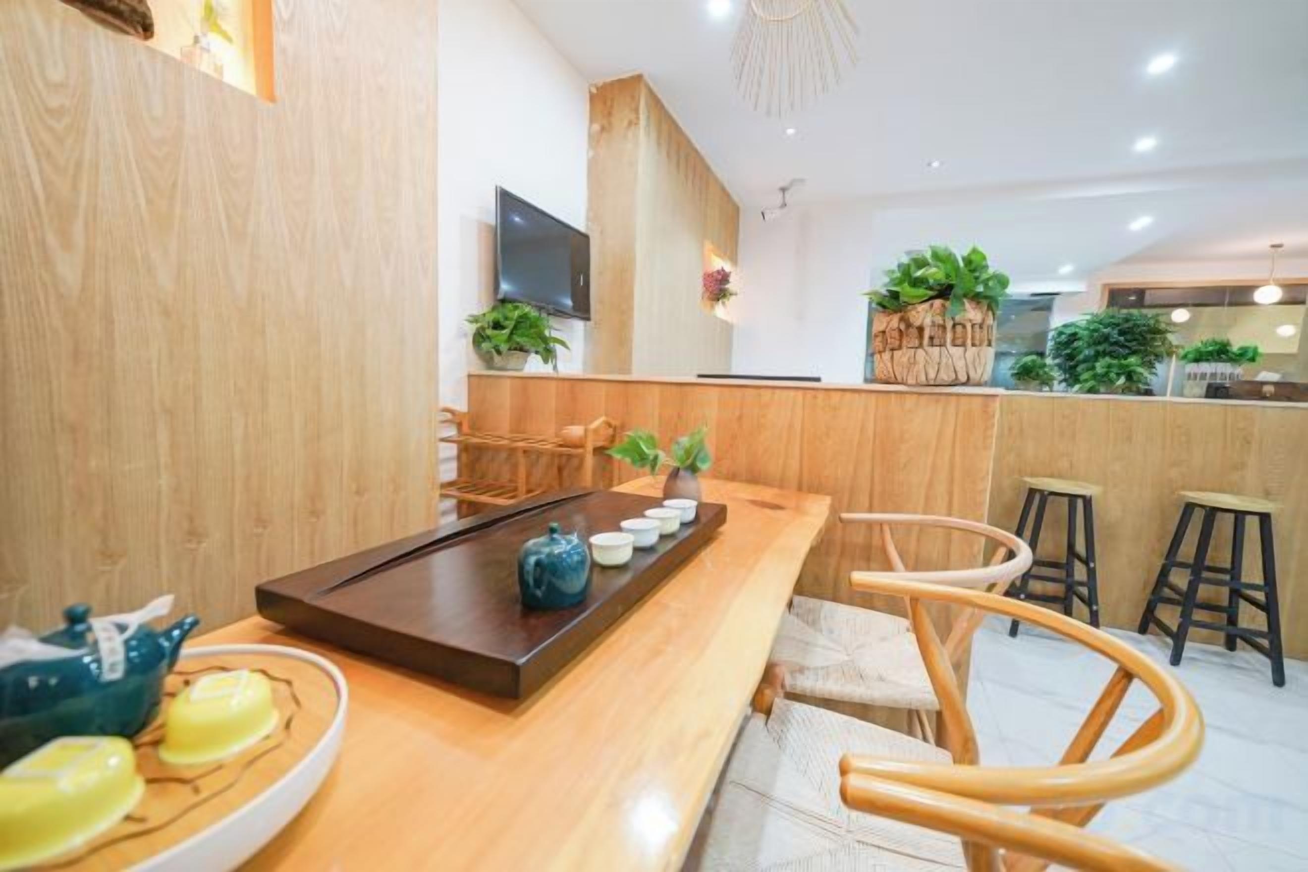 A modern interior with a wooden reception desk, seating area, and a TV mounted on the wall.