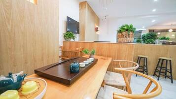A modern interior with a wooden reception desk, seating area, and a TV mounted on the wall.