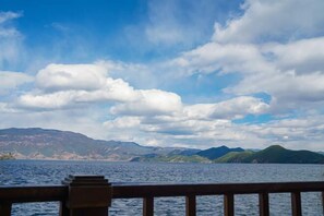 Vista de un cuerpo de agua con montañas al fondo y una baranda de madera en primer plano.