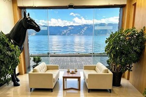 Quarto com uma grande janela, uma estátua de cavalo preto, dois sofás, uma pequena mesa e um vaso de planta.