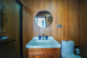 Un baño de madera con lavamanos, espejo e inodoro.