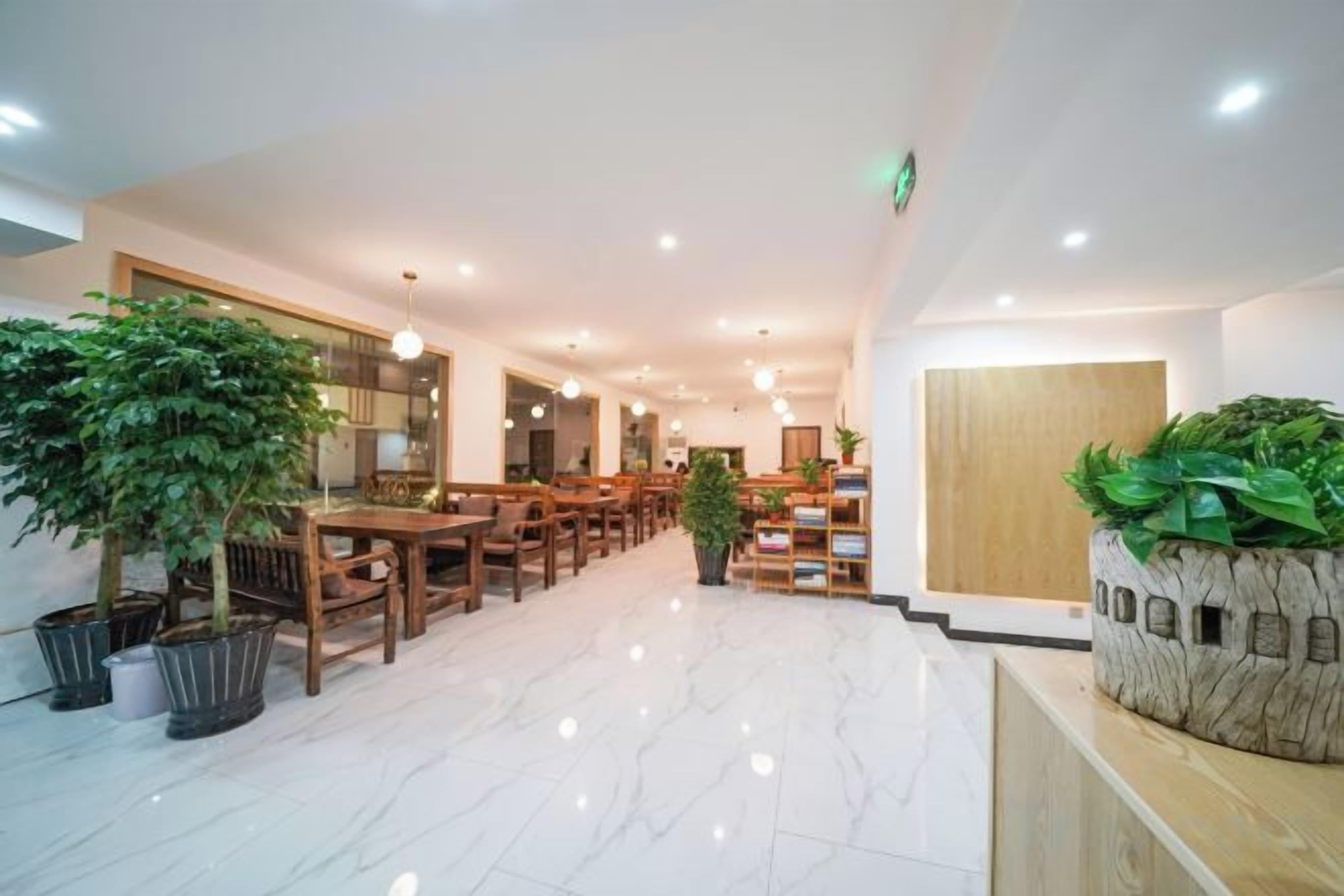 A hotel lobby with wooden furniture, potted plants, and a reception desk.