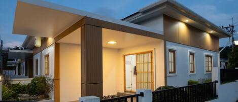 Une maison moderne à deux étages, dotée d’un porche abrité, d’une porte bien visible et d’un petit jardin.