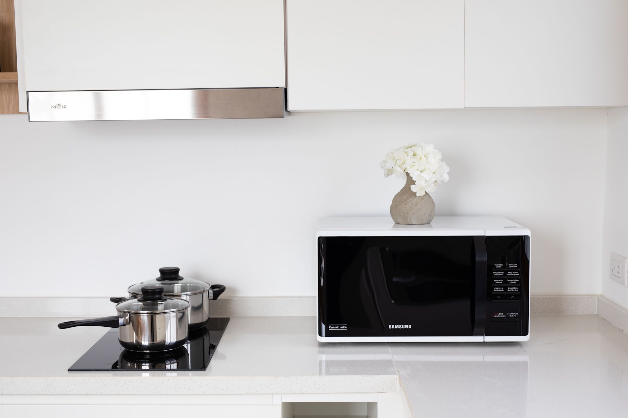 A kitchen with a microwave, a gas stove, and a vase with flowers.