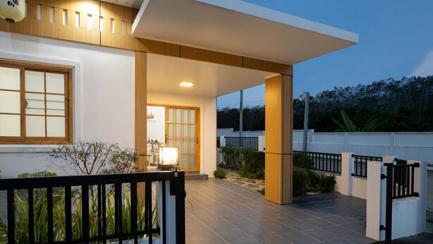 Une maison moderne dotée d’un porche abrité, d’une clôture en bois et d’une entrée bien éclairée.