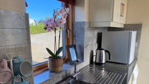 Una cocina moderna con un lavamanos de acero inoxidable, una cafetera y una orquídea en maceta.