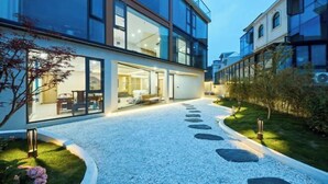 A modern building with large windows, a gravel pathway, and a well-maintained garden.