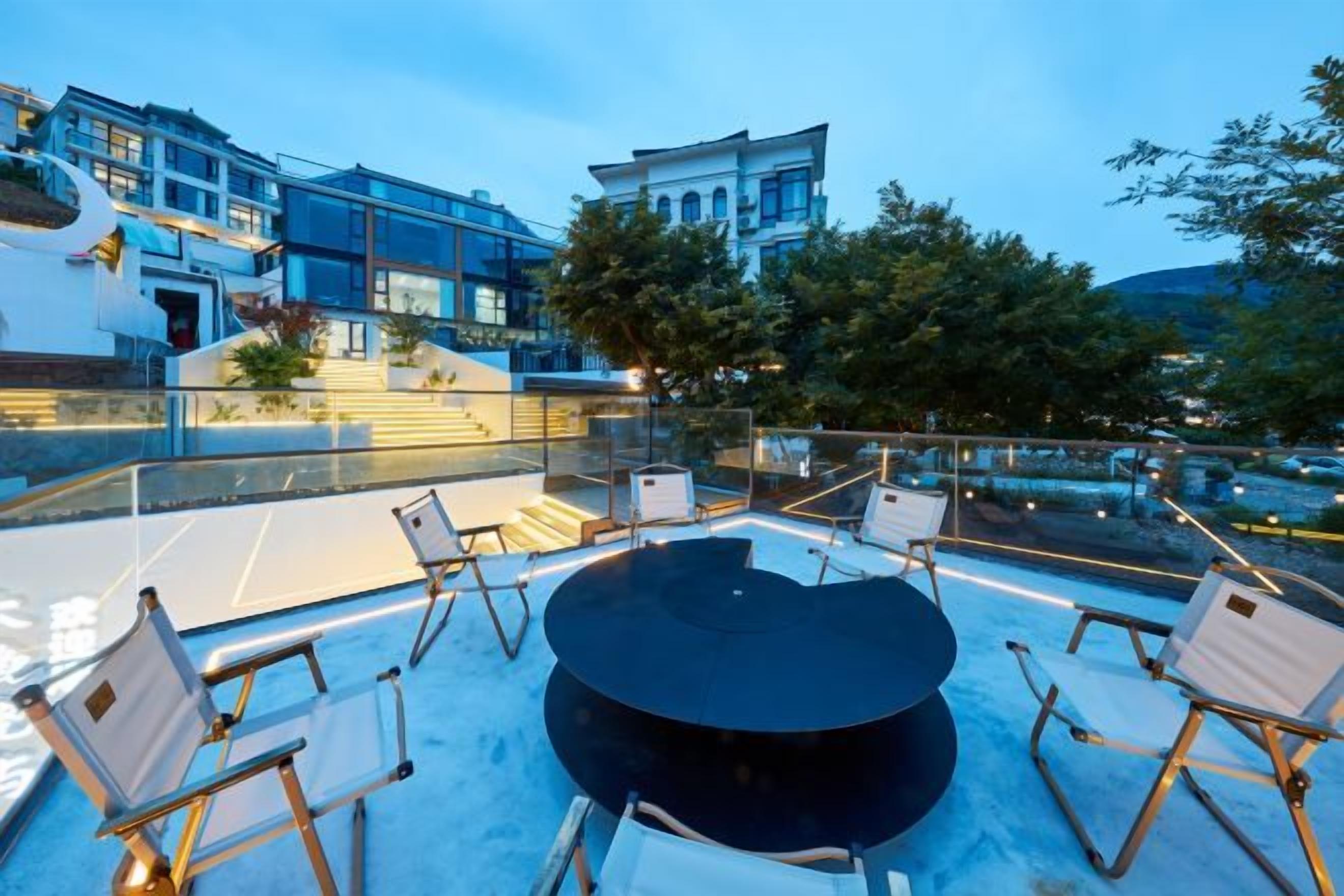A rooftop terrace with a round table and chairs, a glass balustrade, and a view of a building with classical architecture.