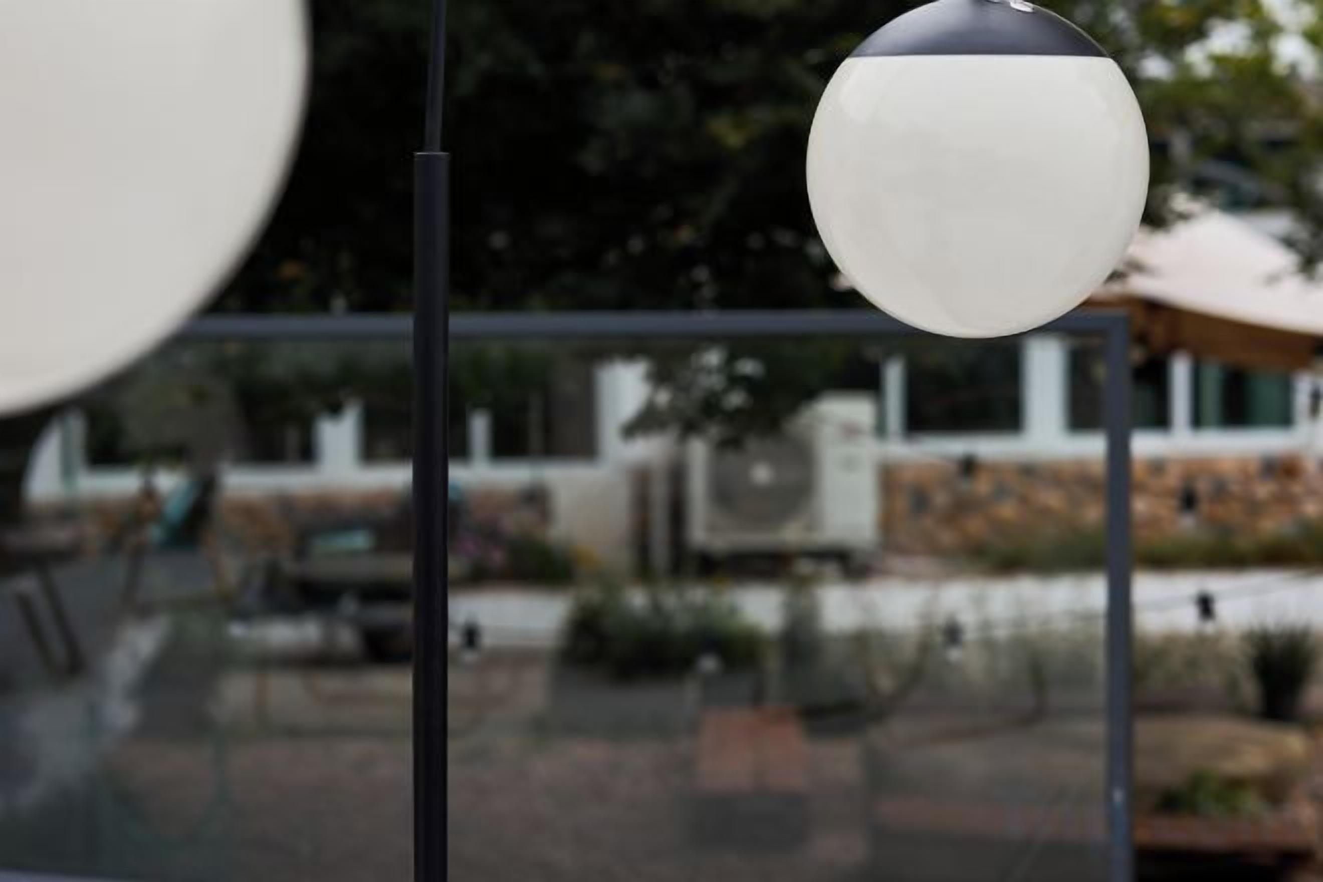 Une cloison en verre avec un objet sphérique, vraisemblablement un luminaire, au premier plan.