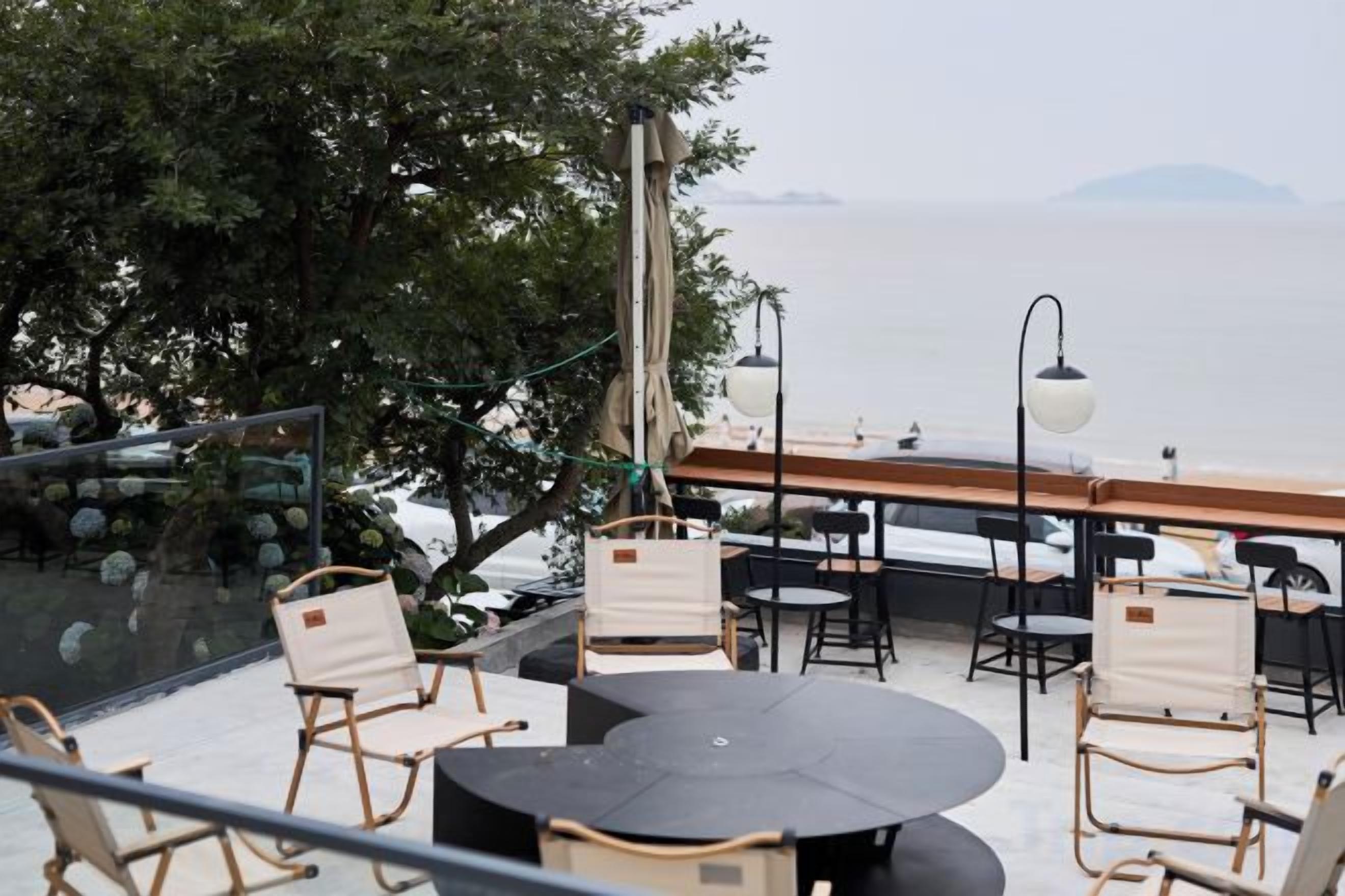 Un espace extérieur aménagé avec des tables et des chaises rondes, offrant une vue sur une étendue d’eau.