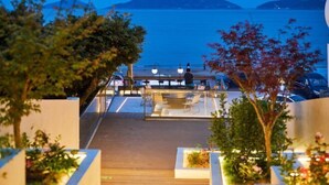 A deck with outdoor seating overlooking a body of water and distant mountains.
