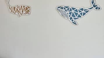Dos adornos de pared con forma de ballena, uno en un tono claro y el otro en azul, sobre una pared lisa.