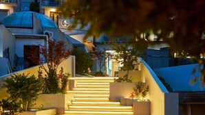 A set of outdoor stairs leading up to a building with a dome structure, surrounded by greenery and illuminated by warm lighting. - Otter Home (Zhoushan)