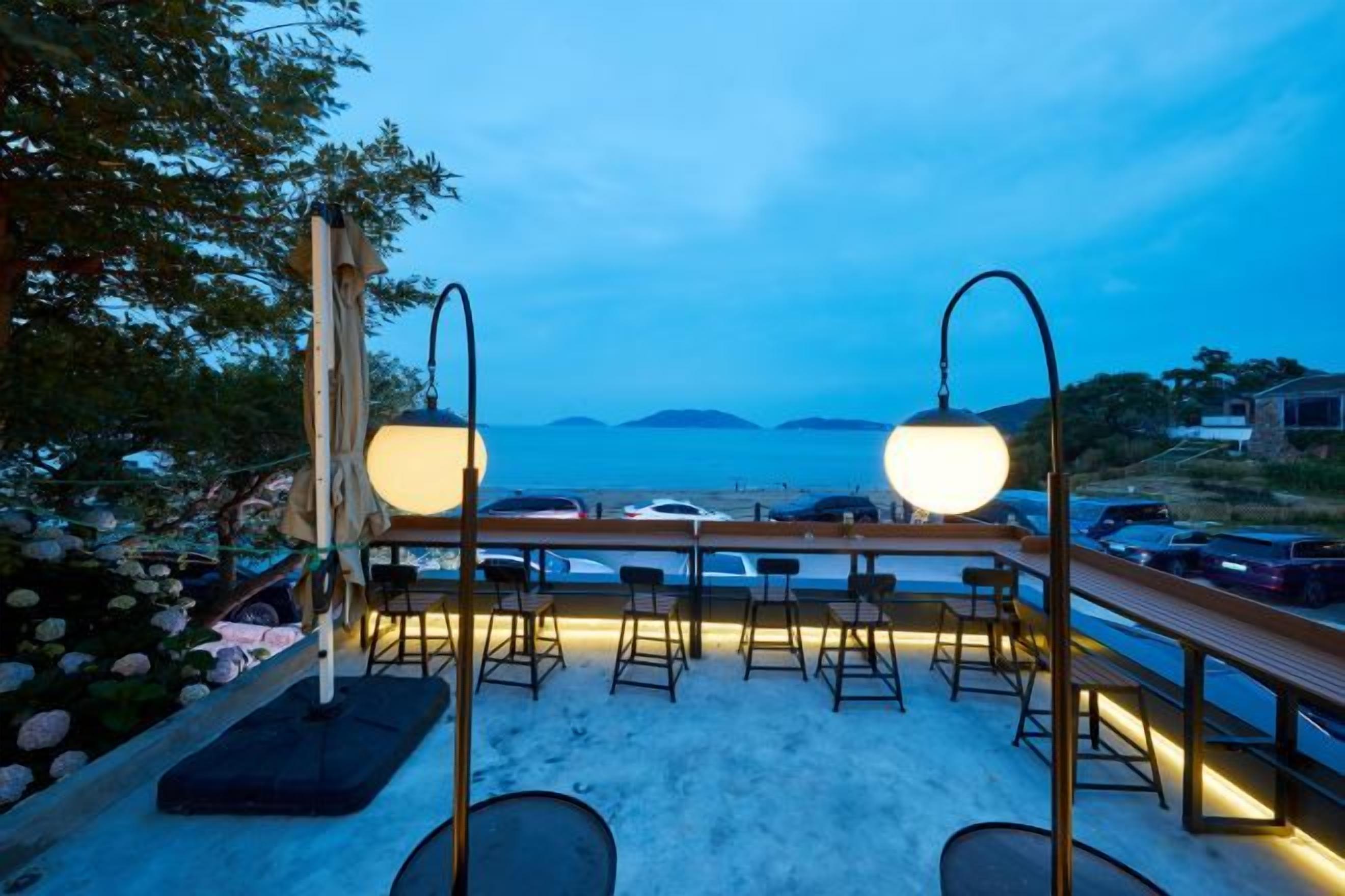 A terrace with outdoor seating, a view of the sea, and a wooden deck.