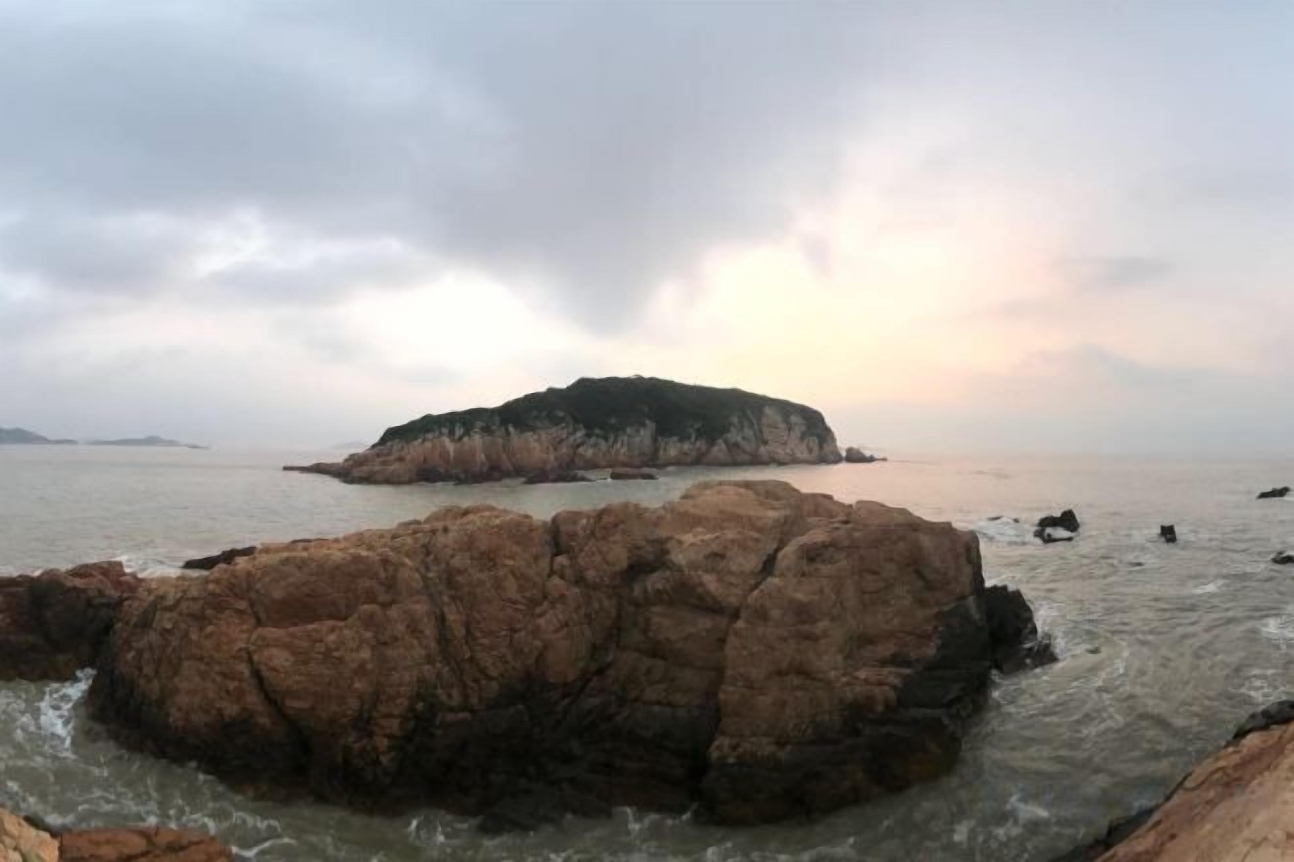 A coastal landscape with rocky formations and calm sea.