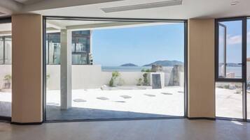 Un interior moderno con un gran ventanal que da a un balcón y vistas al mar.