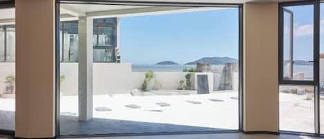 Ein modernes Interieur mit einer großen Glasdoor, die auf einen Balkon mit Meerblick führt.