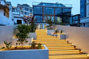 A staircase leading to a modern building with glass windows and a flat roof. - Otter Home (Zhoushan)