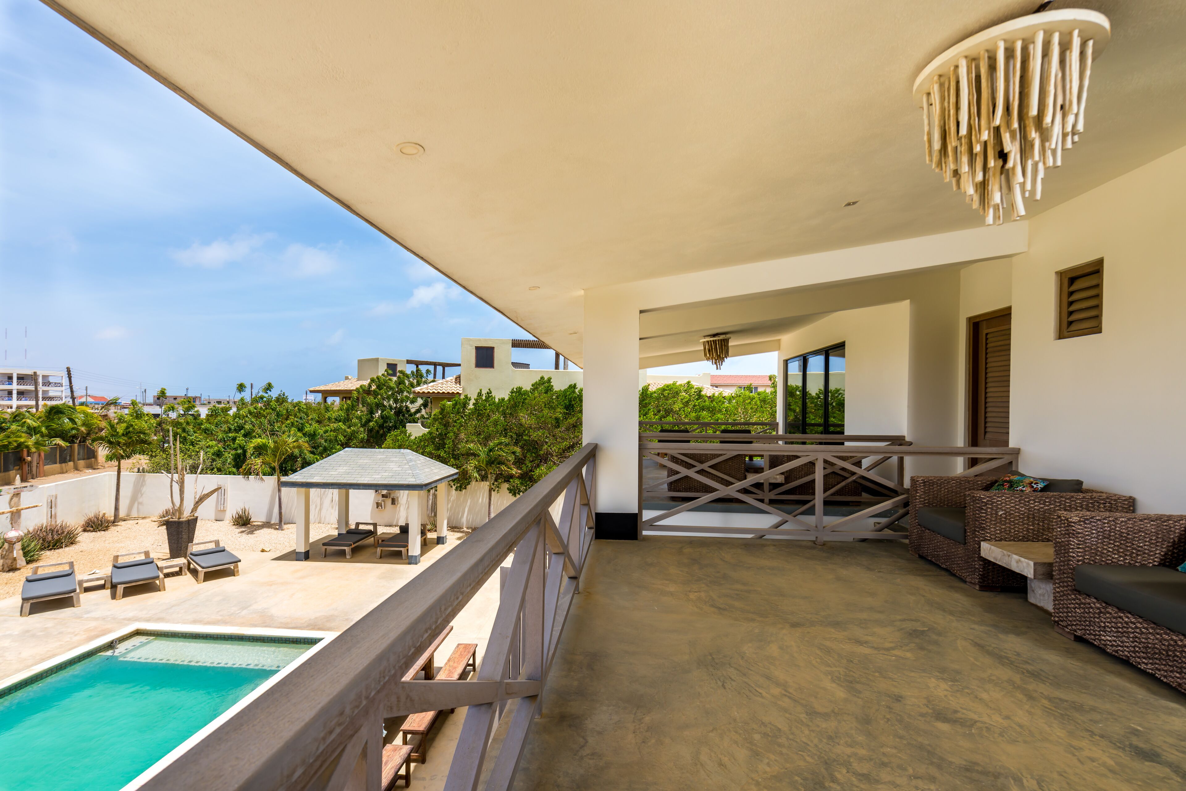 A balcony with a pool, outdoor furniture, and a view of the surrounding area.