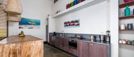 A modern kitchen with wooden cabinets, a central island, and a hanging light fixture.