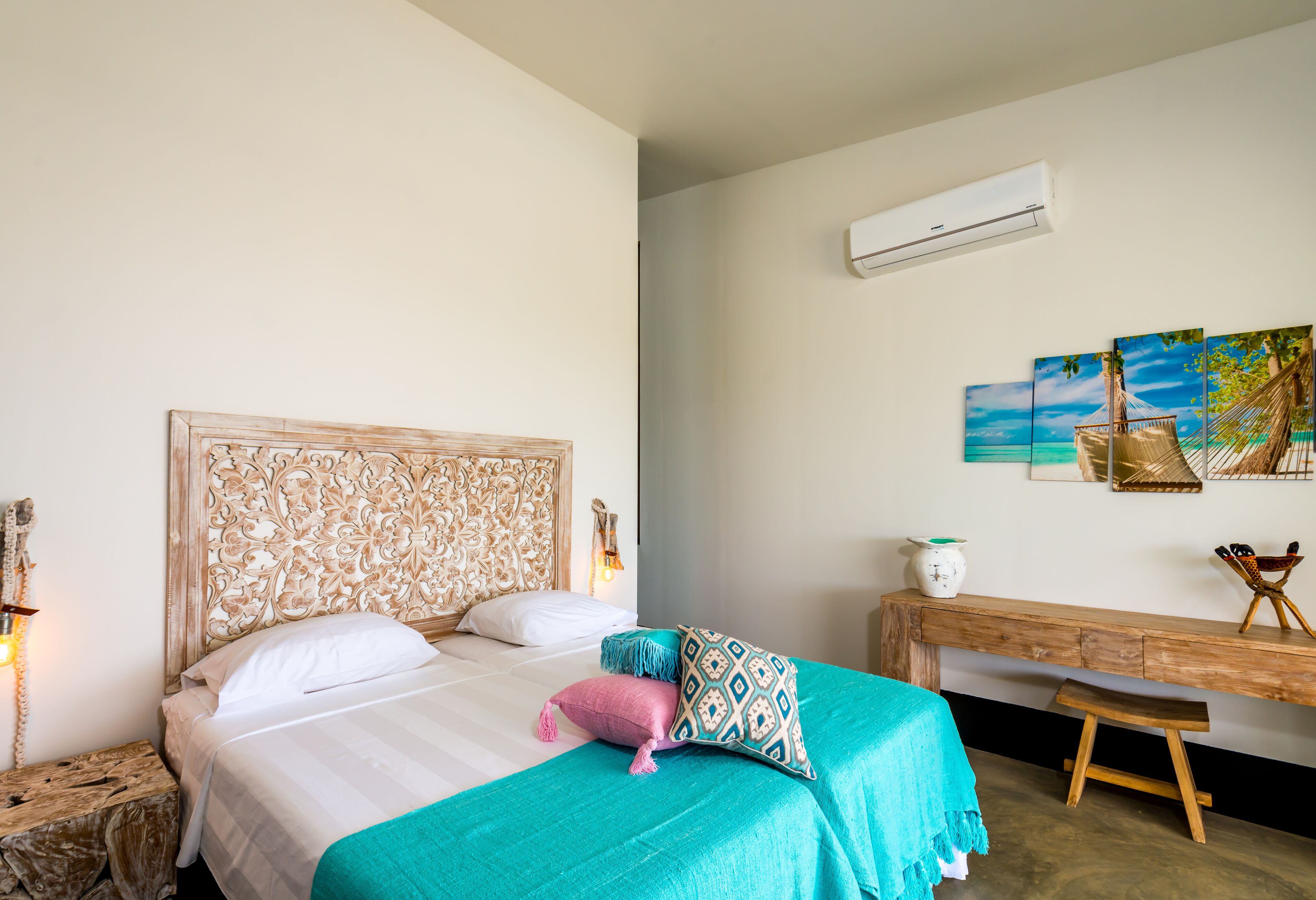 Una camera da letto con un letto grande, una testiera in legno, una panca e un condizionatore d'aria a muro.