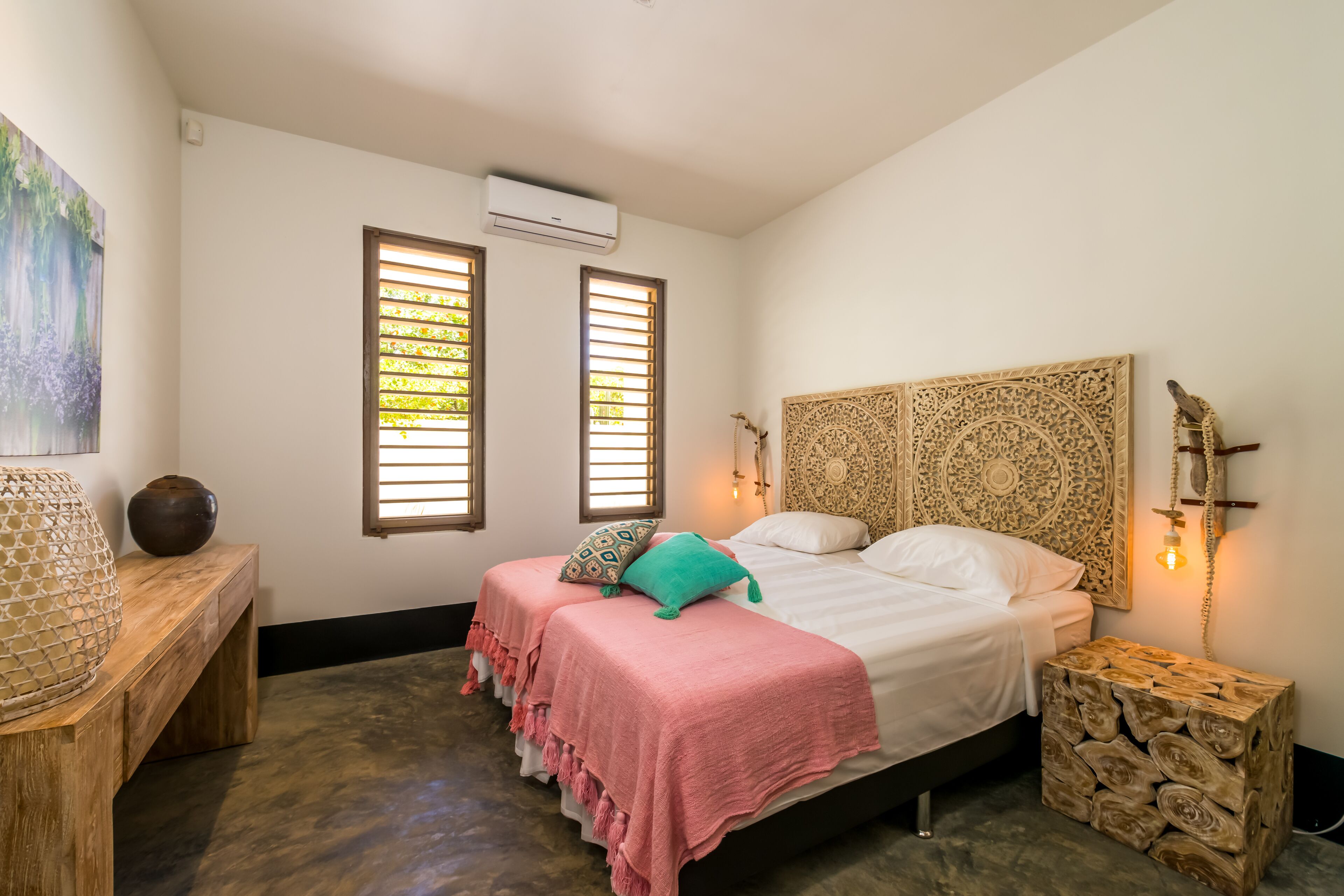 A bedroom with a bed, bedside tables, a decorative headboard, and a wall-mounted phone.