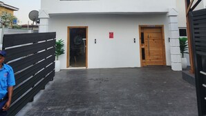 Un bâtiment moderne à deux étages, doté d’un espace d’accueil, d’une entrée sécurisée par un portail et d’un panneau d’avertissement indiquant la présence d’une clôture électrique.