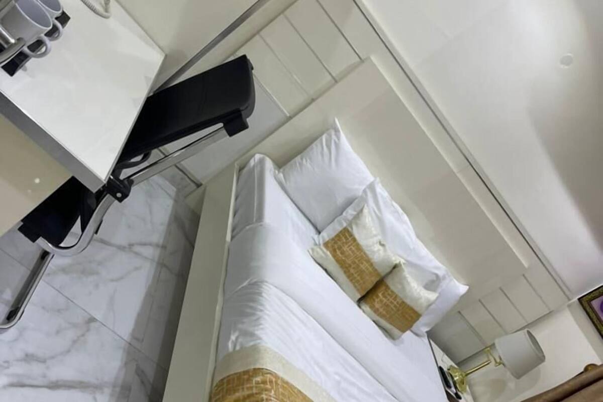 Quarto de hotel com cama, mesa de cabeceira, espelho e banheiro com pia e vaso sanitário.