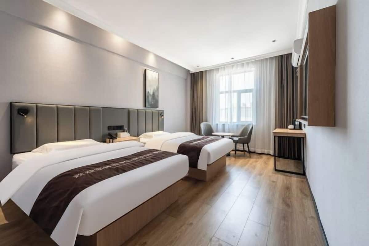 Una habitació d'hotel amb dos llits, un escriptori i una cadira.