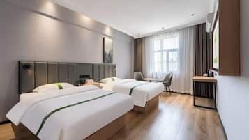 Une chambre d’hôtel avec deux lits, un bureau, une chaise et une grande fenêtre avec des rideaux.