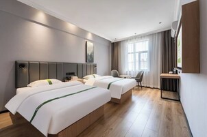 Habitación de hotel con dos camas, un escritorio, una silla y un ventanal con cortinas.