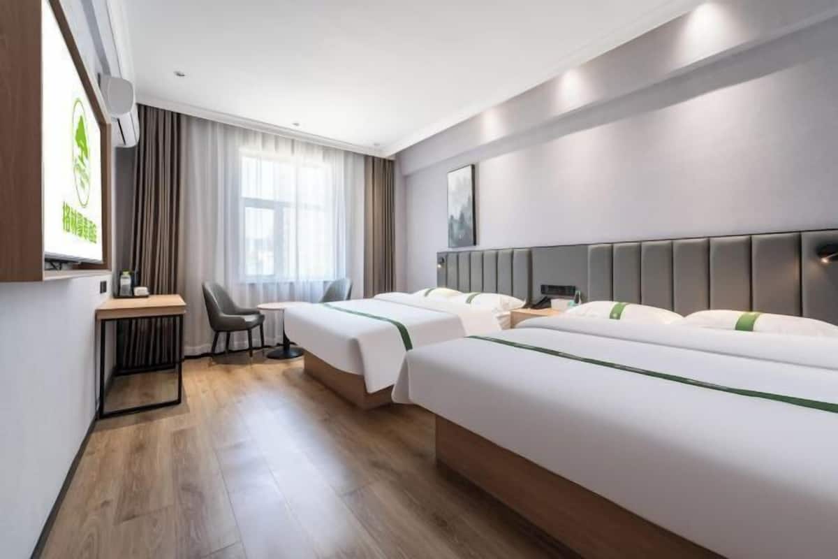 Habitació d'hotel amb dos llits, un escriptori i una cadira.
