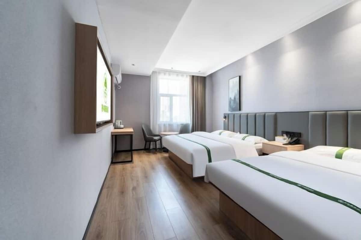 Habitació d'hotel amb dos llits, una taula de treball, una cadira i una finestra amb cortines.