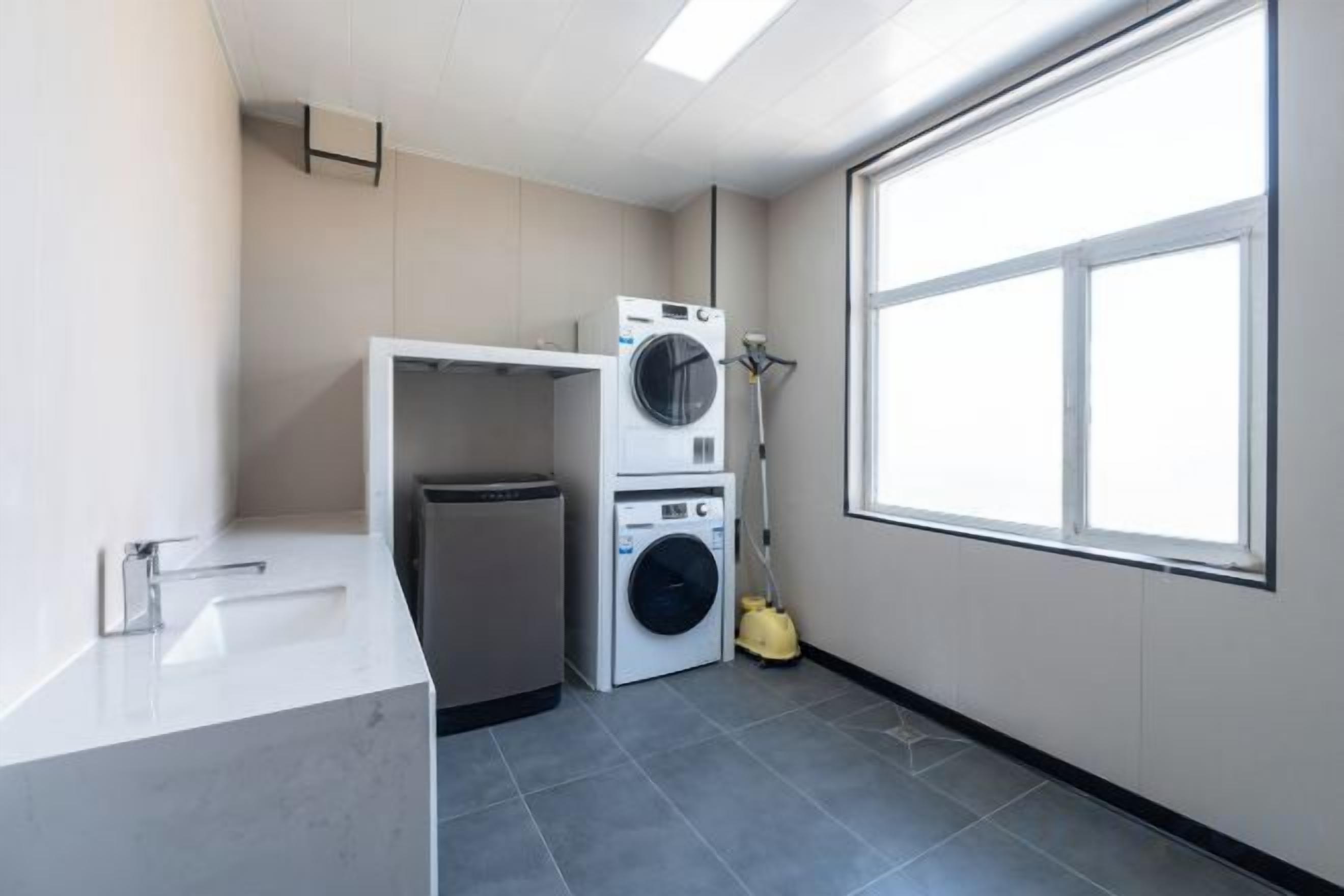 A laundry room with a washing machine, dryer, and a mop.
