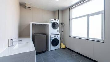 A laundry room with a washing machine, dryer, and a mop.
