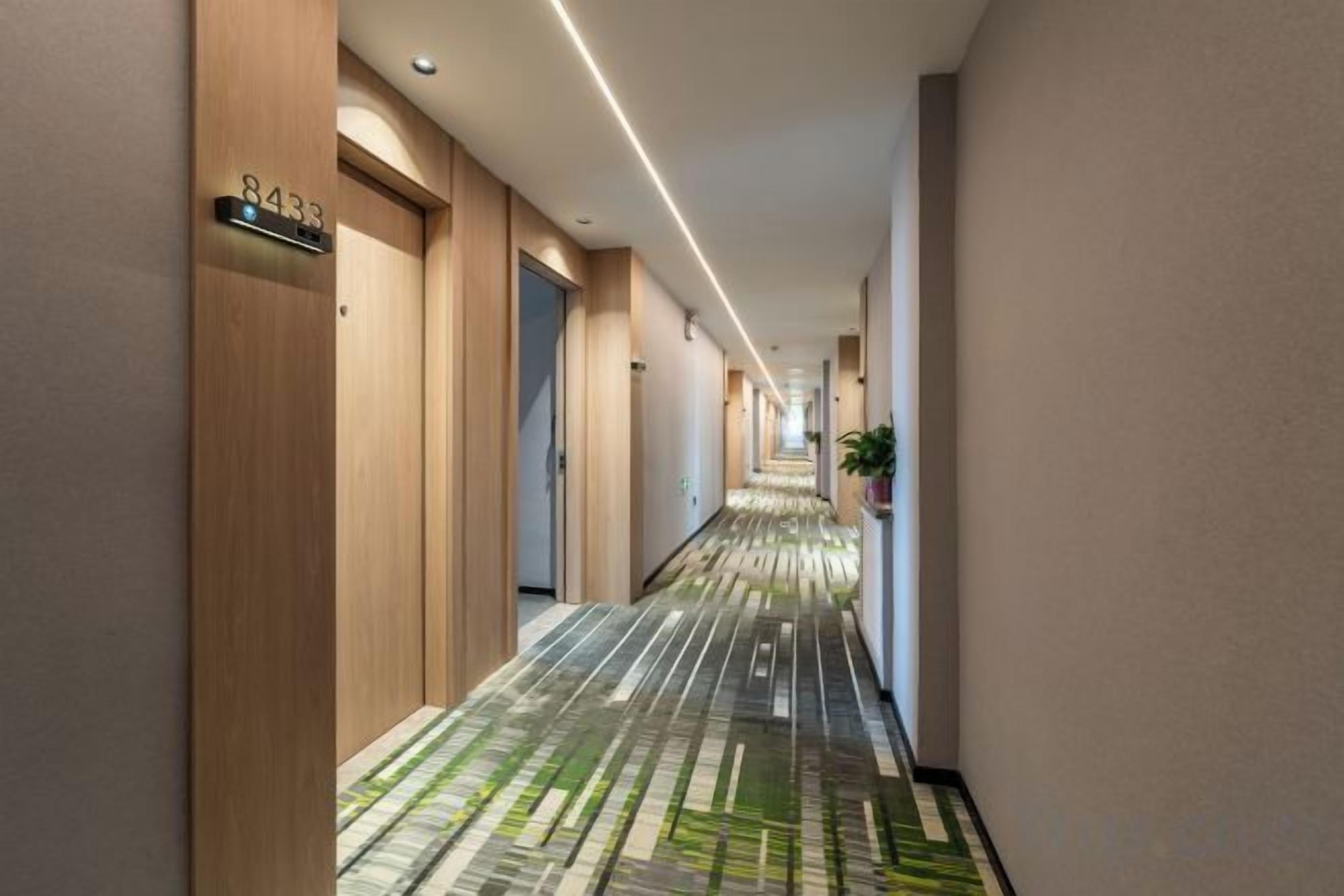 Un pasillo de hotel con puertas de madera, alfombra estampada y un cartel que indica la habitación 8433.